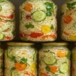 Ako tražite zdrav i starinski recept za zimnicu bez konzervansa i sirćeta, onda je mešana salata bez konzervansa pravi izbor! Ova salata se kiseli potpuno prirodno, kao kiseli kupus, i ostaje hrskava i osvežavajuća tokom cele zime. Priprema je jednostavna – povrće se isecka, posoli, ostavi da pusti sok i prirodnom fermentacijom postaje ukusna i zdrava salata koja je odličan prilog uz svako jelo. 📌 Potrebni sastojci 1 kg šargarepe 1 kg paprika 1 kg krastavacaZimnica bez konzervansaPrirodna zimnica 2 kg kupusa 1 kg zelenog paradajza ½ kg karfiola 200 g soli 📌 Priprema mešane salate – korak po korak Priprema povrća: Šargarepu krupno izrendajte.Kiseli kupusPovrće bez konzervansa Krastavce isecite na tanke kolutove. Papriku nasecite na trake. Zeleni paradajz i karfiol isecite na sitnije komade. Kupus isecite kao za salatu. Mešanje: Sve isečeno povrće sjedinite, dodajte so i dobro promešajte. Punjenje tegli: Mešavinu sipajte u staklene tegle, pritisnite i stavite plastične pritiskače. Fermentacija: Tegle stavite na dublji poslužavnik, prekrijte krpom i ostavite 2–3 dana da „rade“ i izbace višak tečnosti.Slani dodatakPrirodna zimnica Zatvaranje: Kada prestane da izbija tečnost, prekrijte celofanom i zatvorite. Tegle čuvajte na hladnom i tamnom mestu. Saveti Uvek koristite trećinu kupusa u odnosu na količinu povrća – on je ključ za prirodnu fermentaciju. Povrće možete kombinovati po želji (karfiol, celer, kornišoni, zelene paprike). Ne dodaje se sirće, vinobran ni konzervans – salata se kiseli potpuno prirodno. Najlepša je kada odstoji barem 3–4 nedelje i ukusi se sjedine. Ova mešana salata bez konzervansa je savršen prilog uz sarme, pečenja, suhomesnato ili bilo koje kuvano jelo. Osvežava i daje poseban ukus svakoj trpezi, a idealna je za ljubitelje zdrave, domaće hrane.Kiseli kupusPovrće bez konzervansa creativabox.com